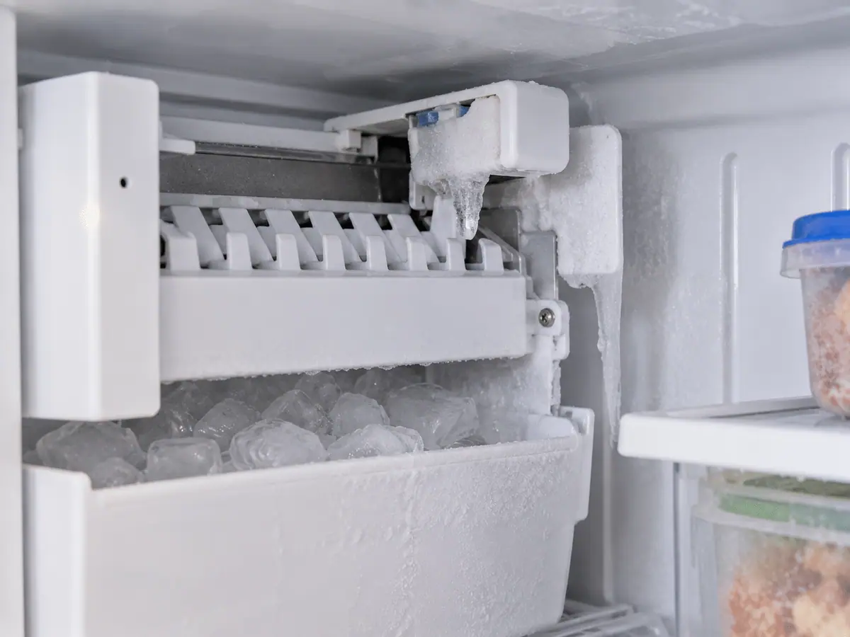 Small ice buildup and frozen droplets near a refrigerator ice maker