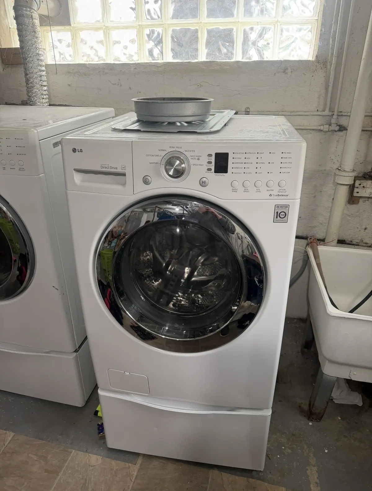 LG front-load washer on a pedestal in a basement