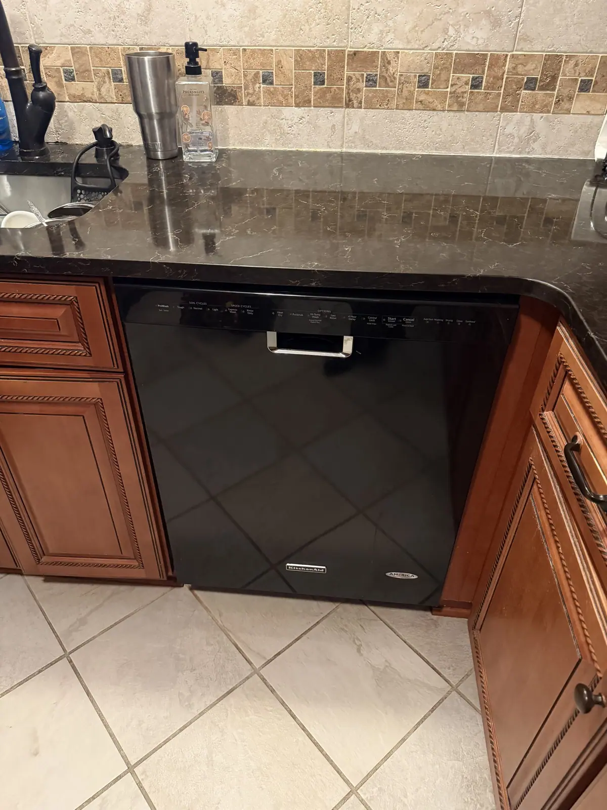 Black dishwasher under a granite countertop